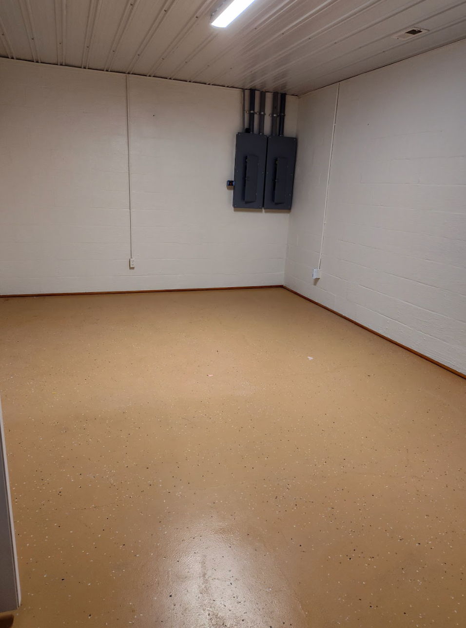 An empty room with a brown floor and white walls