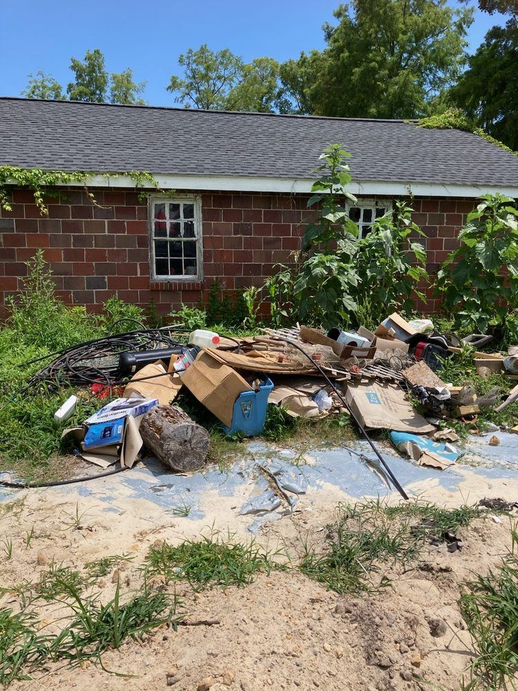 A pile of trash is in front of a brick house.