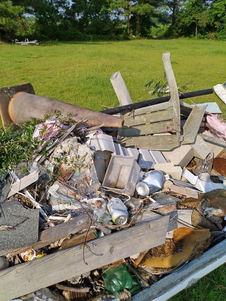 A pile of trash is sitting on top of a trailer in a field.