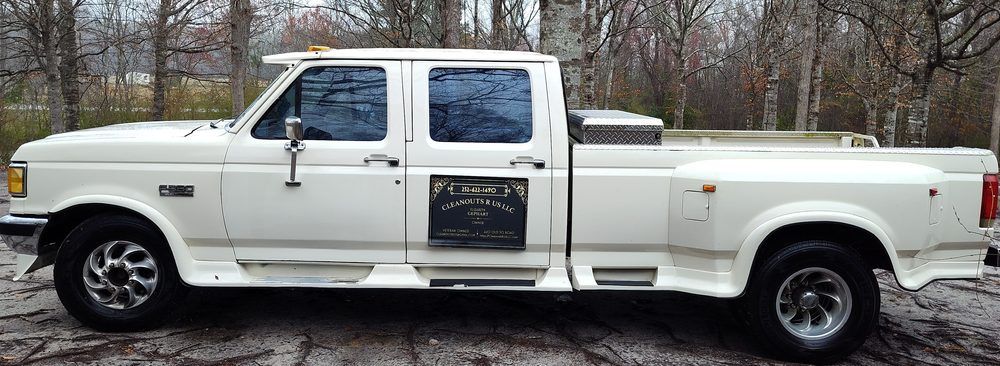 A white truck is parked in the snow in front of a forest.