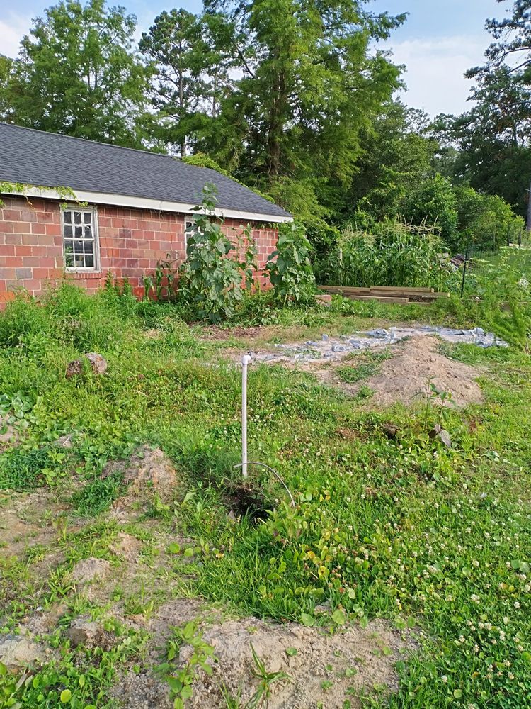 A brick house is sitting in the middle of a grassy field.