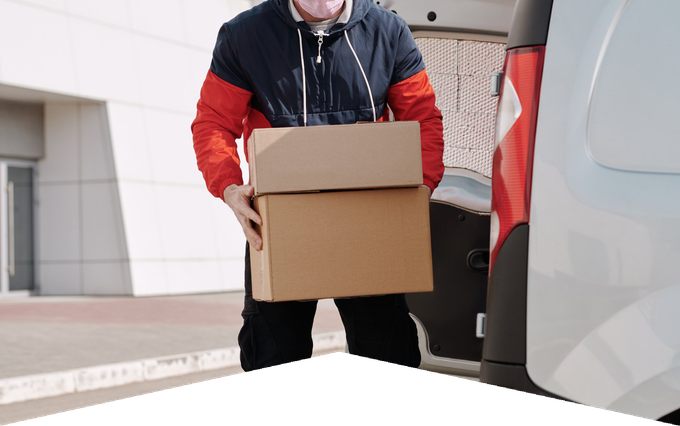 A delivery man is carrying a cardboard box into the back of a van.