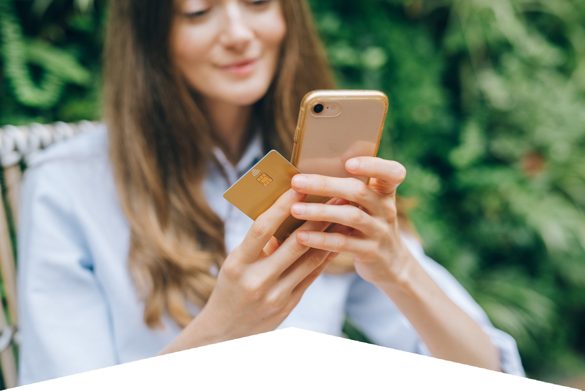 A woman is holding a credit card and a cell phone.