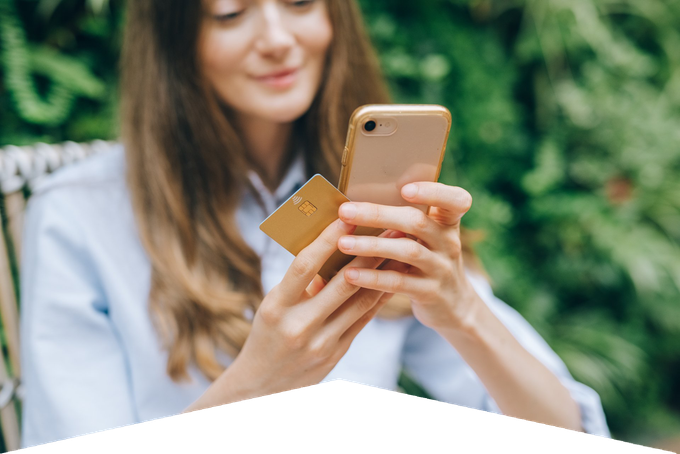 A woman is holding a credit card and a cell phone.