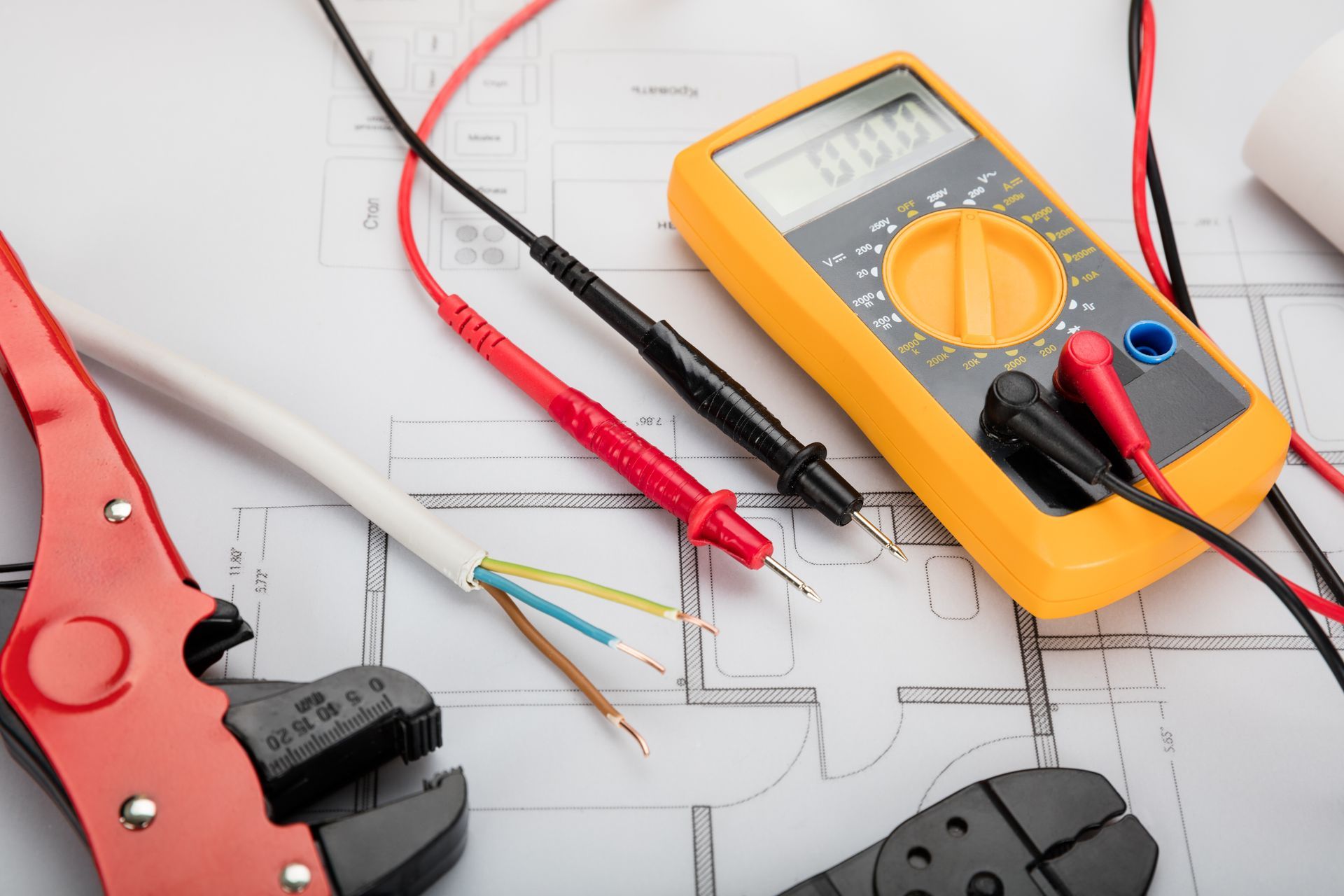 A digital multimeter is sitting on top of a blueprint.
