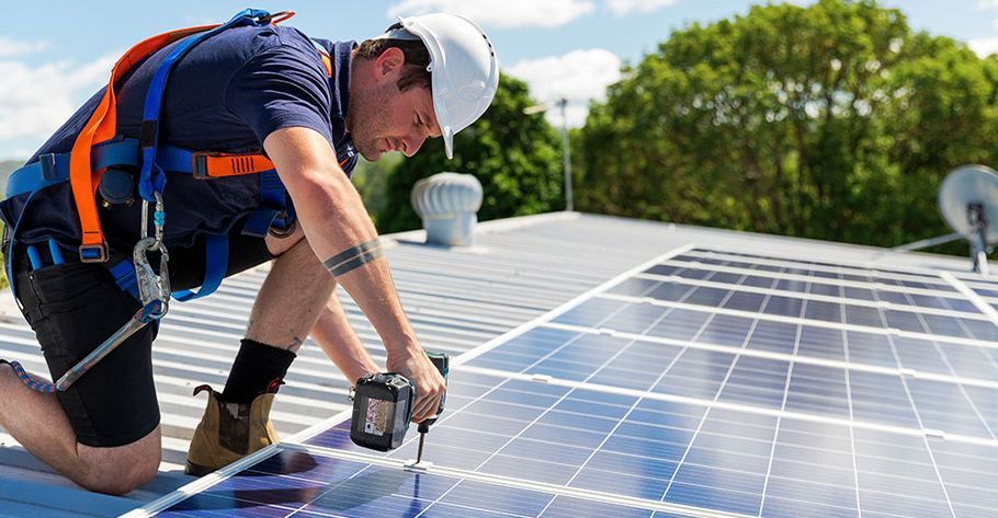 A man is installing solar panels on the roof of a building.