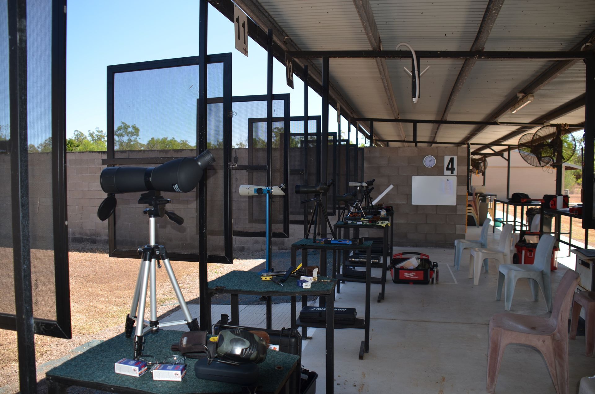 Shooting range: Several tables with equipment, spotting scopes, and safety screens.