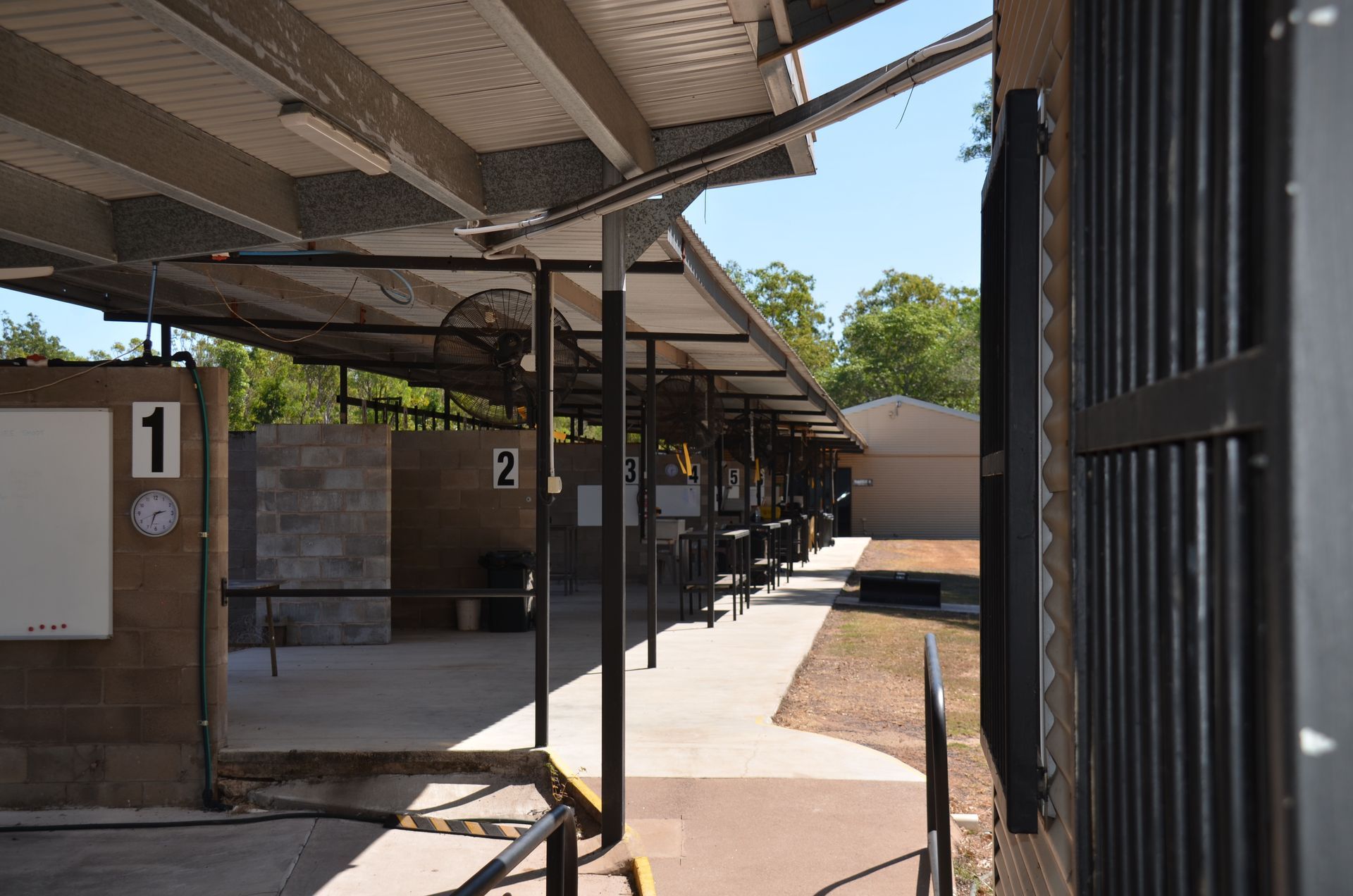 Shooting range with covered shooting lanes, concrete walkway, and numbered stations.