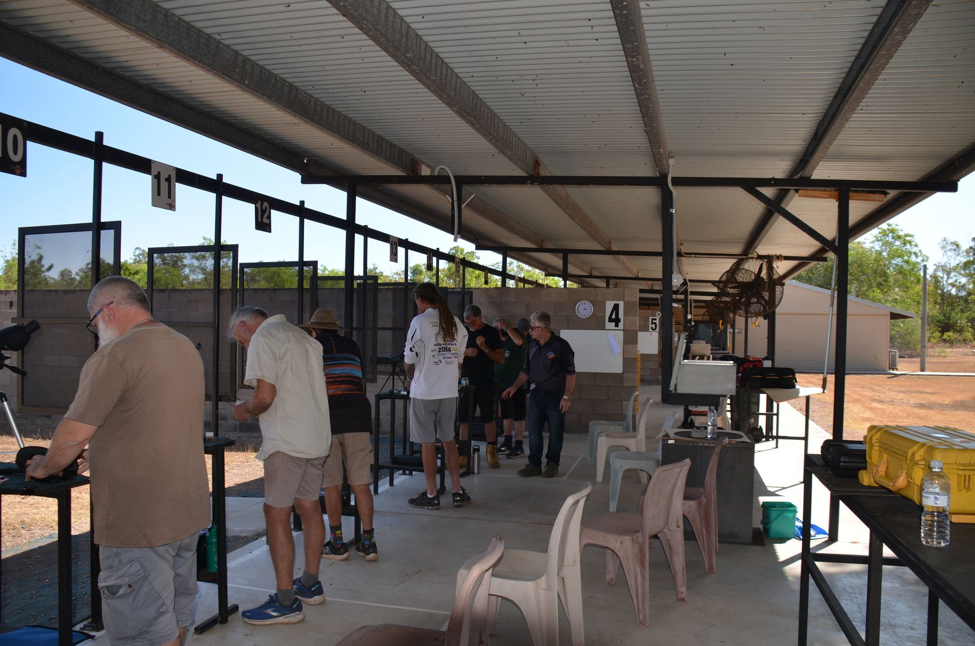 People at an outdoor shooting range, preparing to shoot.