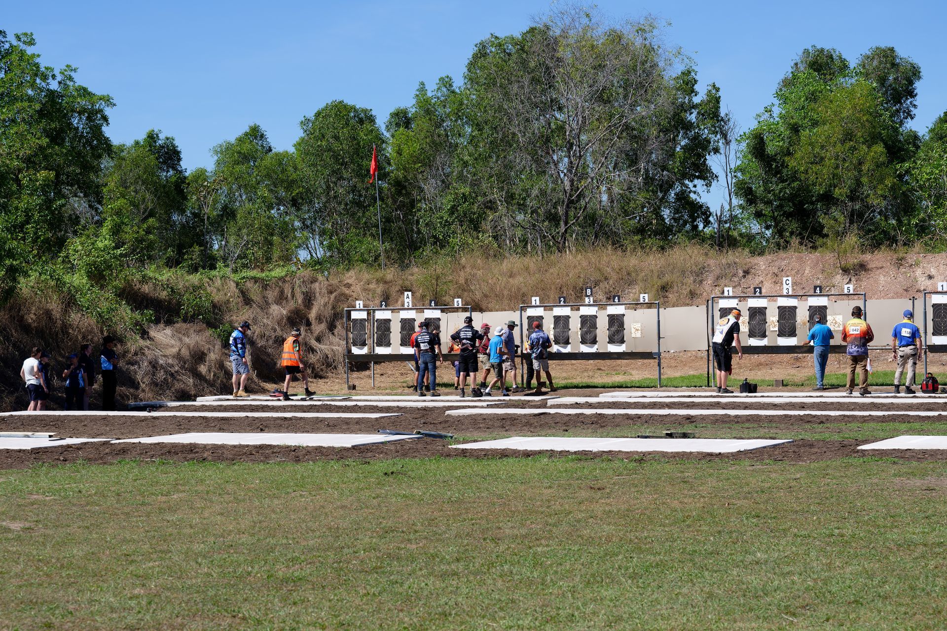 People at a shooting range aiming at targets on a sunny day.