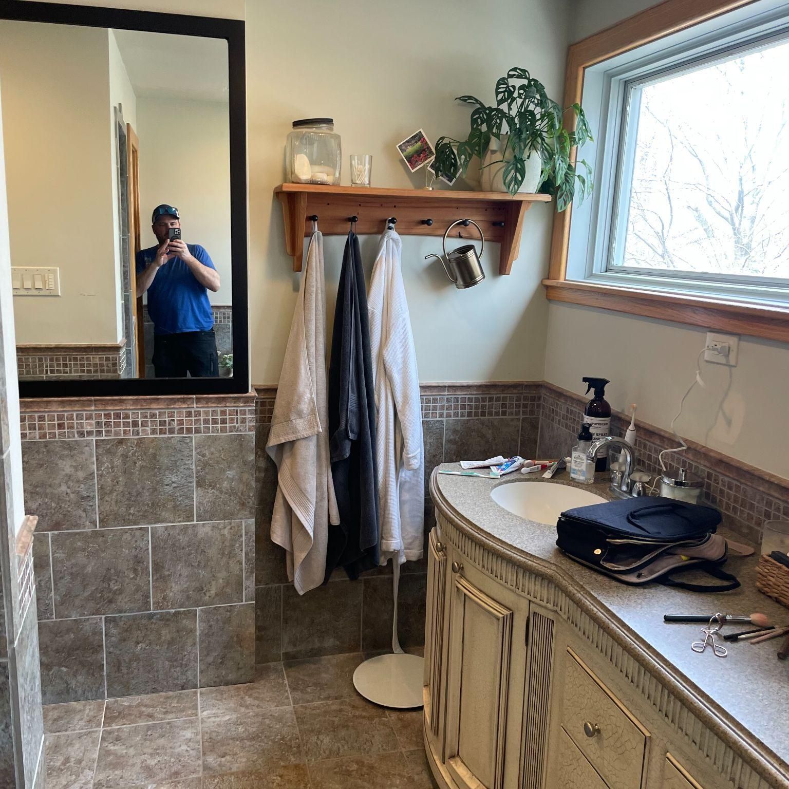 A man is taking a picture of himself in a bathroom mirror