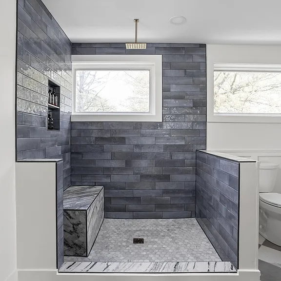 A bathroom with a walk in shower and a window.