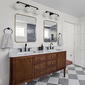 A bathroom with two sinks , two mirrors and a checkered floor.