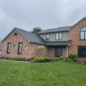 A large brick house with a large lawn in front of it.