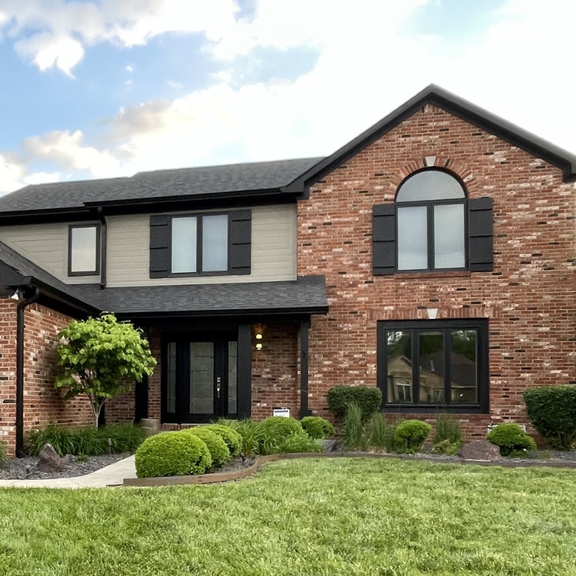 A large brick house with black shutters on the windows