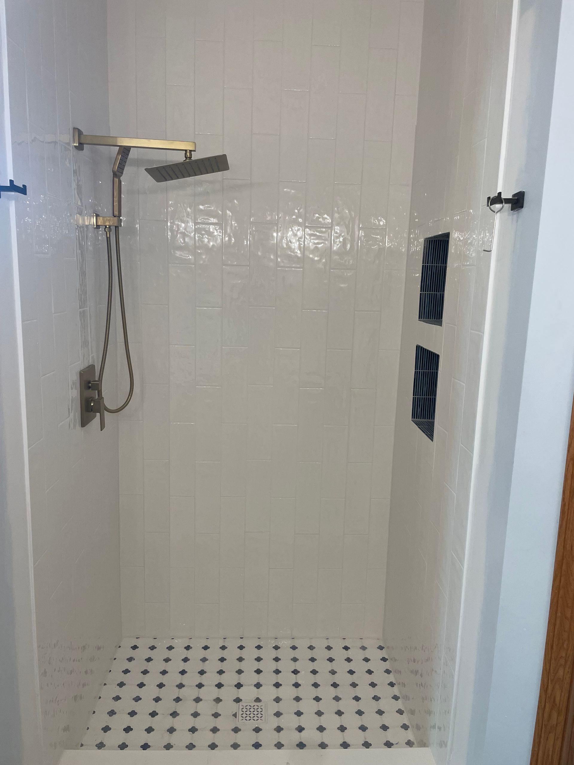 A shower with white tiles and a black and white checkered floor.
