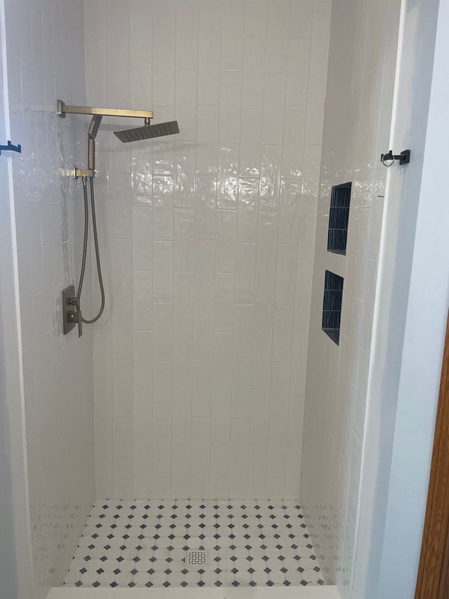 A shower with white tiles and a black and white checkered floor.