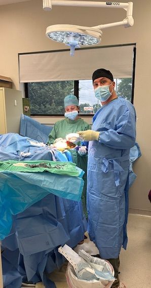 A nurse is working on a dog in an operating room.