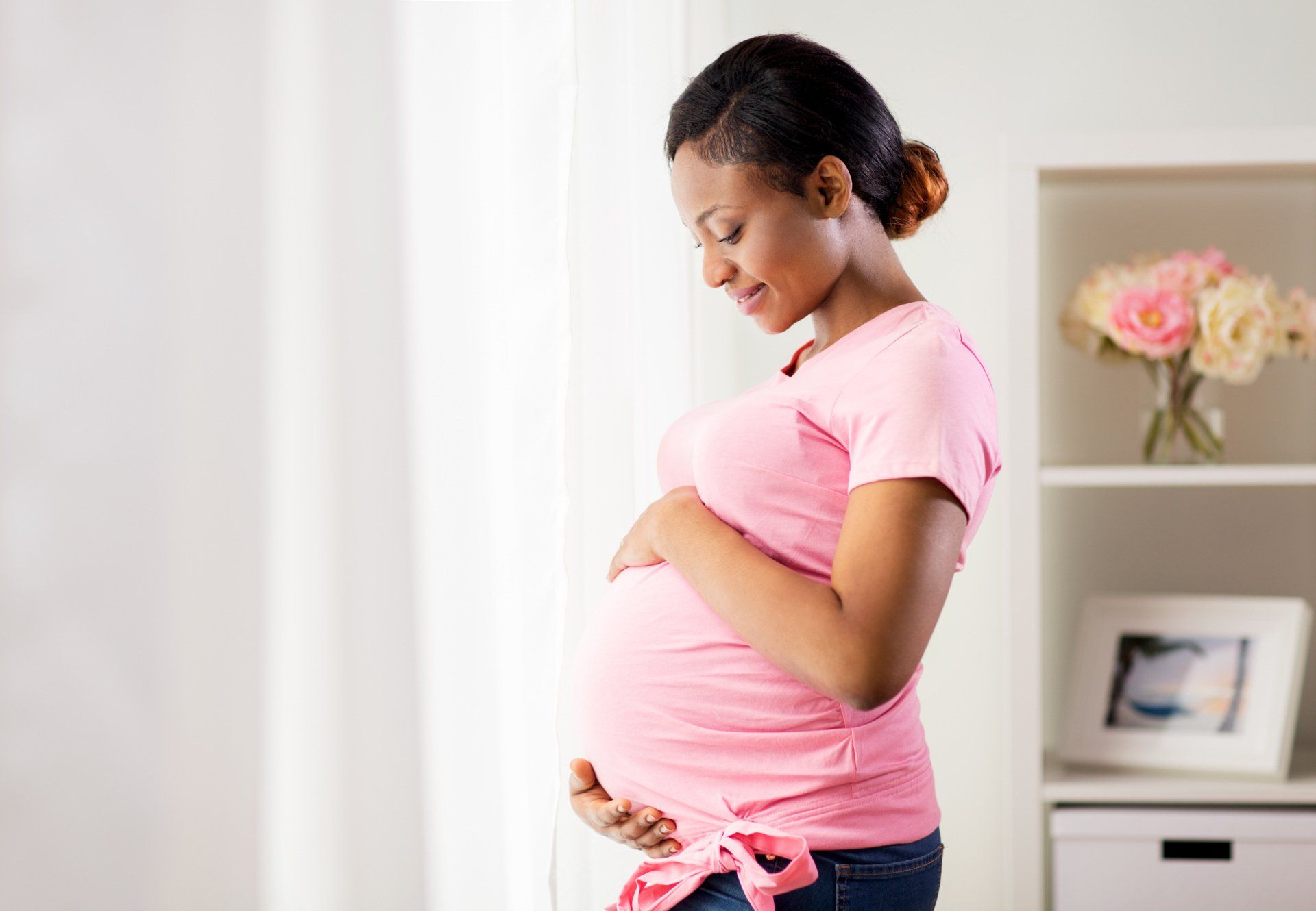 a pregnant woman in a pink shirt is holding her belly