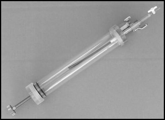 A clear glass tube with a metal handle is sitting on a table