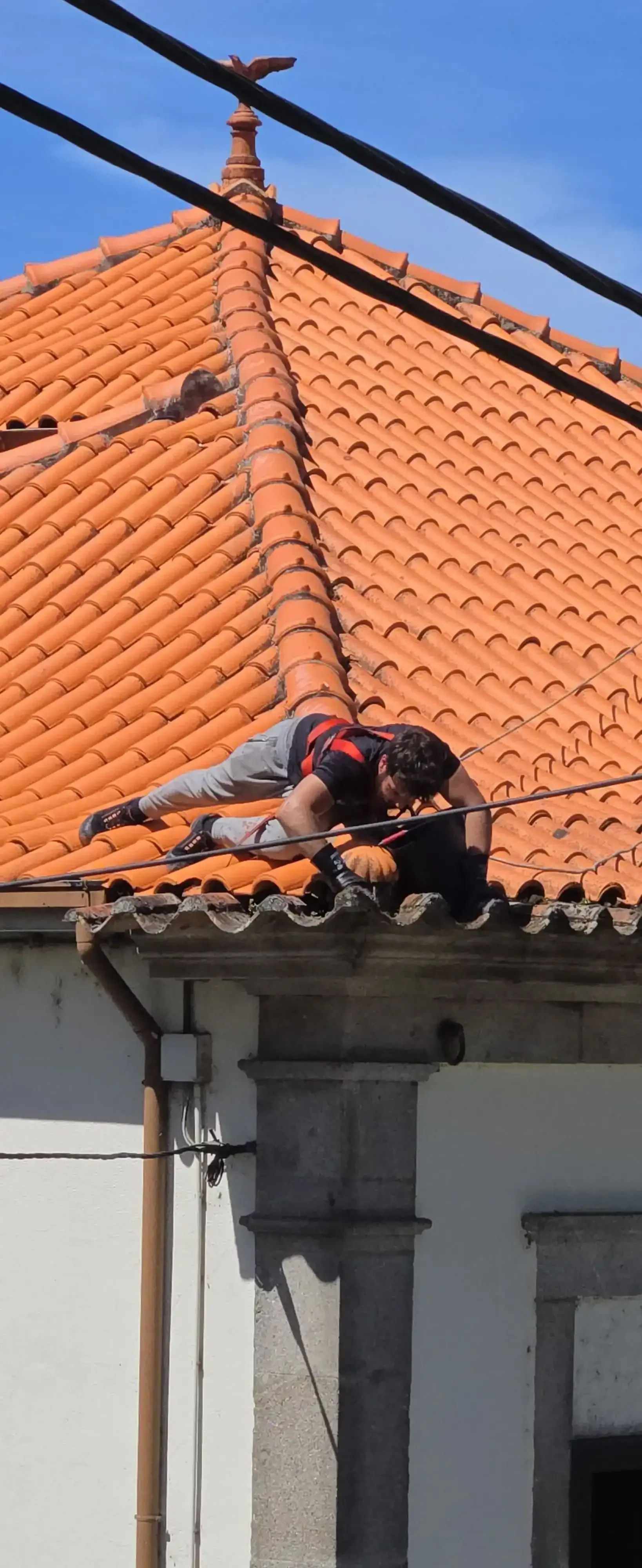 Trabalho em altura na limpeza de telhados no Porto com utilização de arnês e sistema seguro.