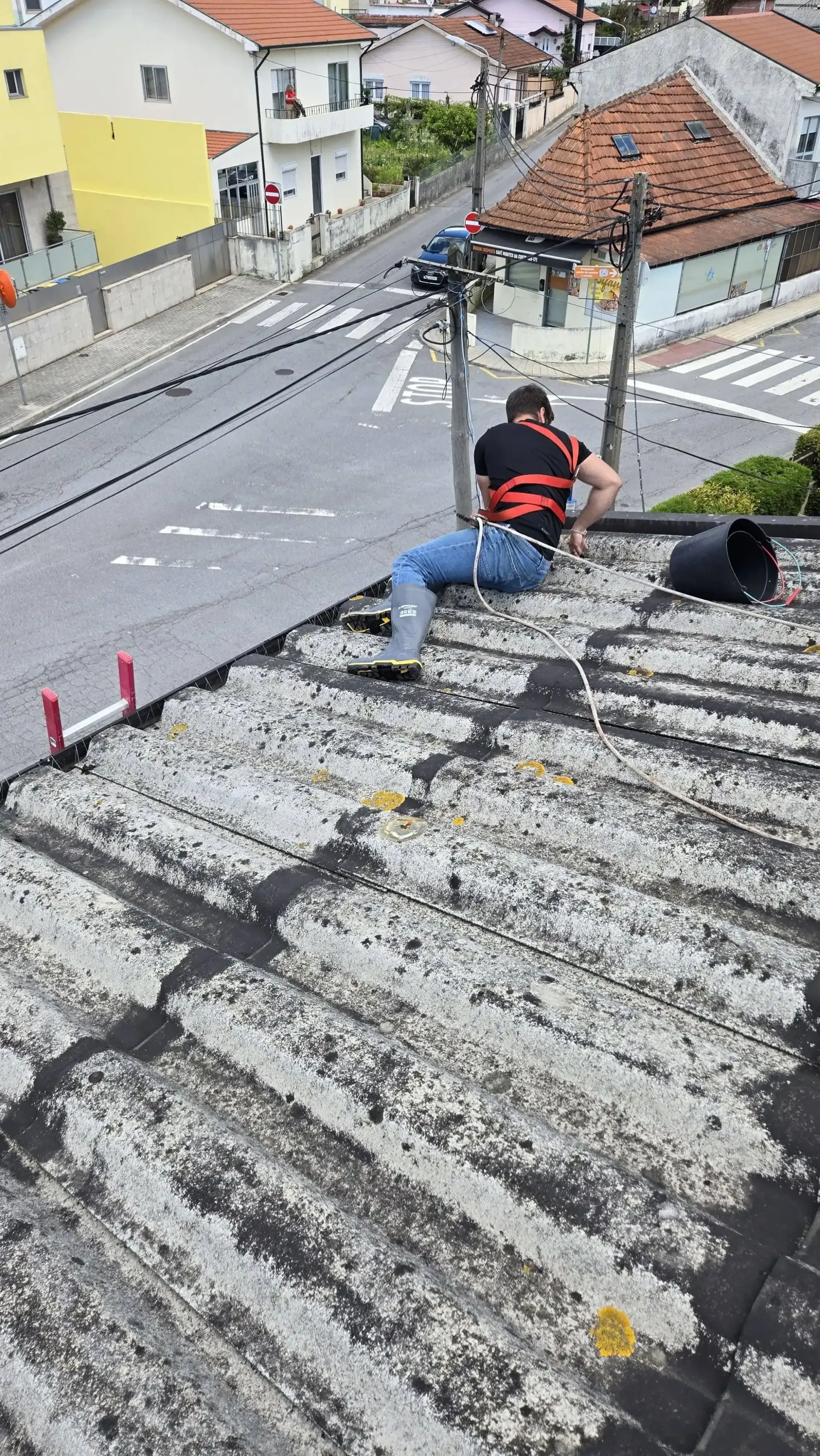 Profissional a realizar limpeza de telhado no Porto com total segurança e arnês de proteção.
