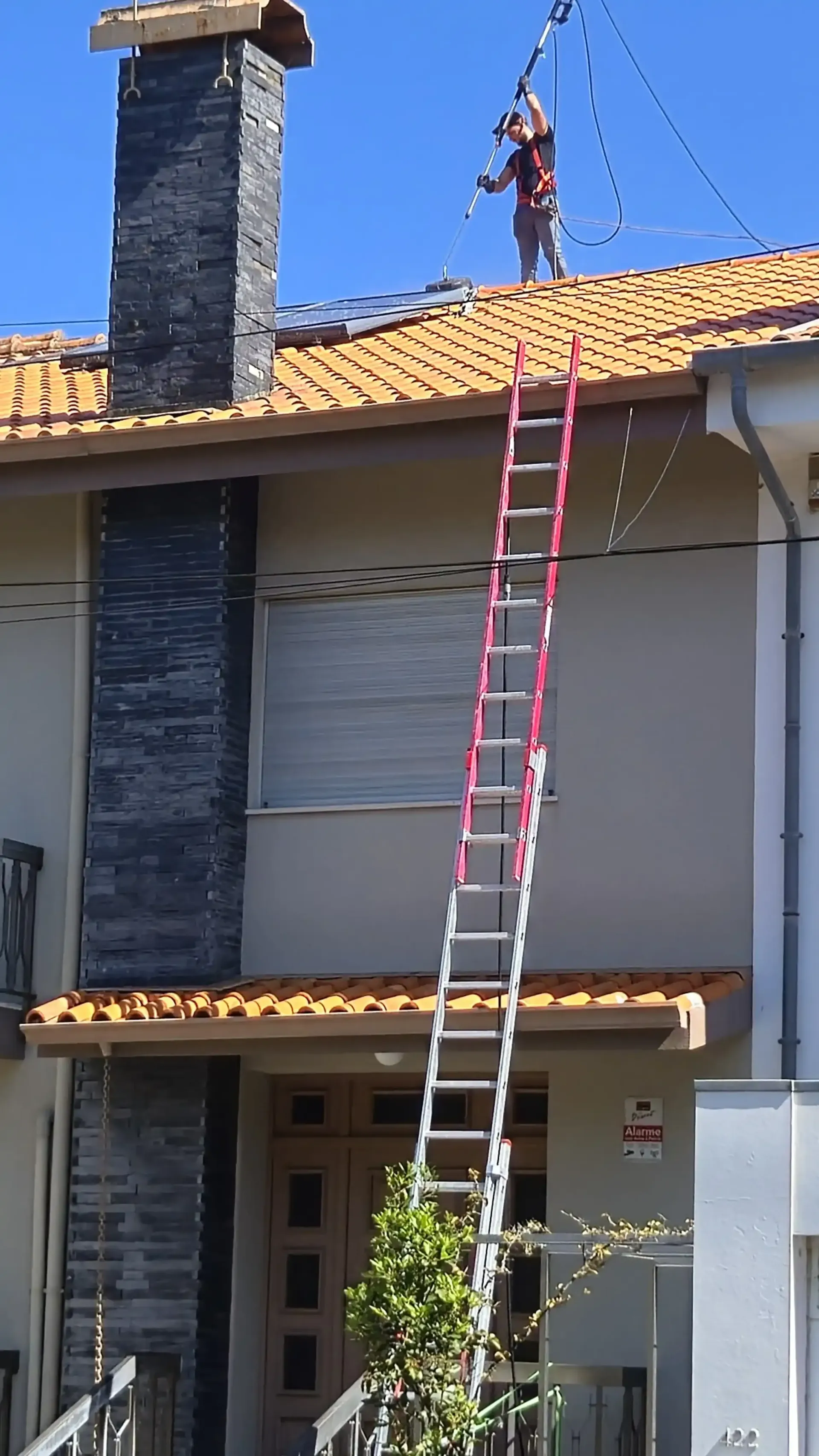 Profissional a realizar limpeza de telhado no Porto com sistema de segurança em altura.