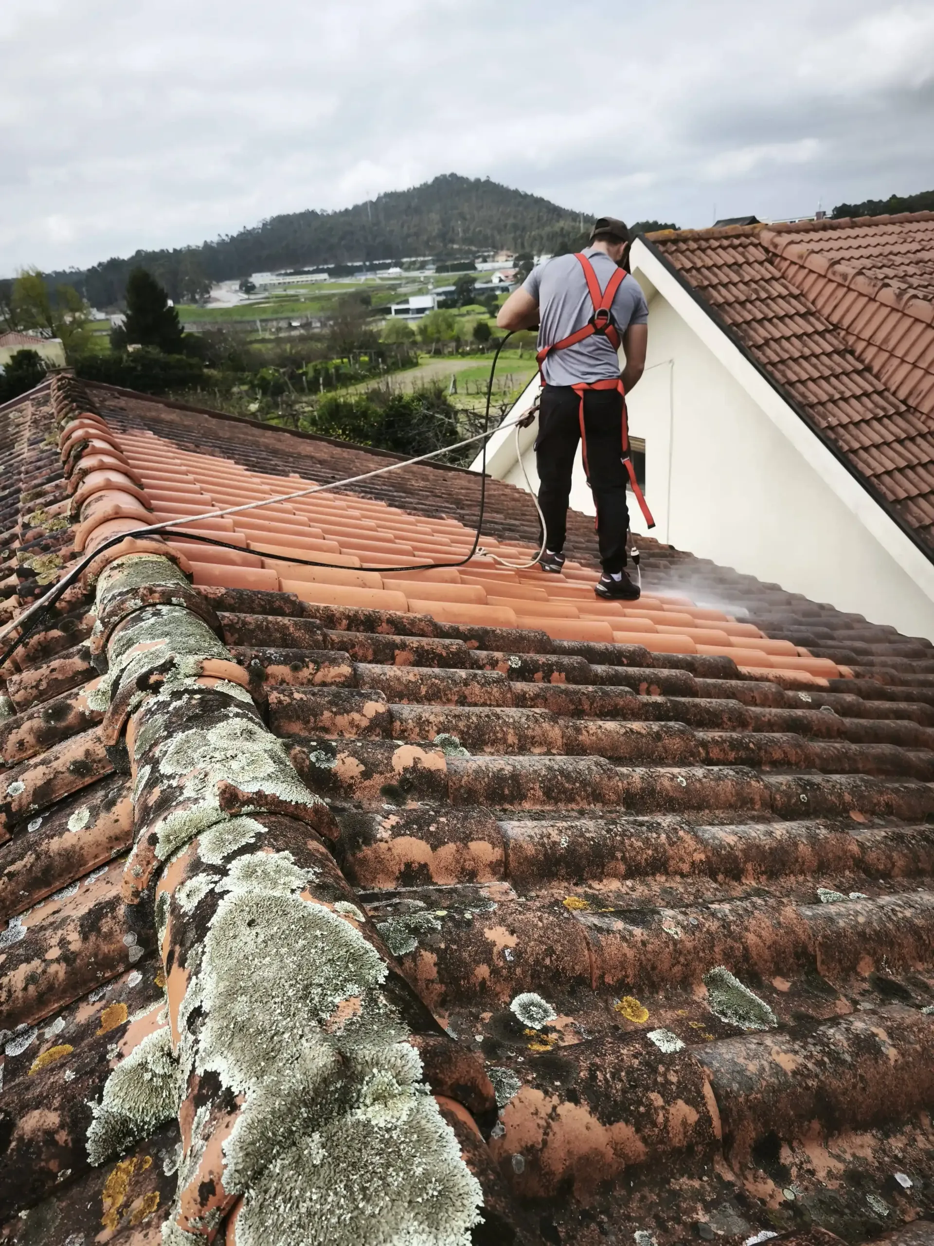 Profissional a realizar limpeza de telhados no Porto com sistema de segurança em altura e lavagem softwash.