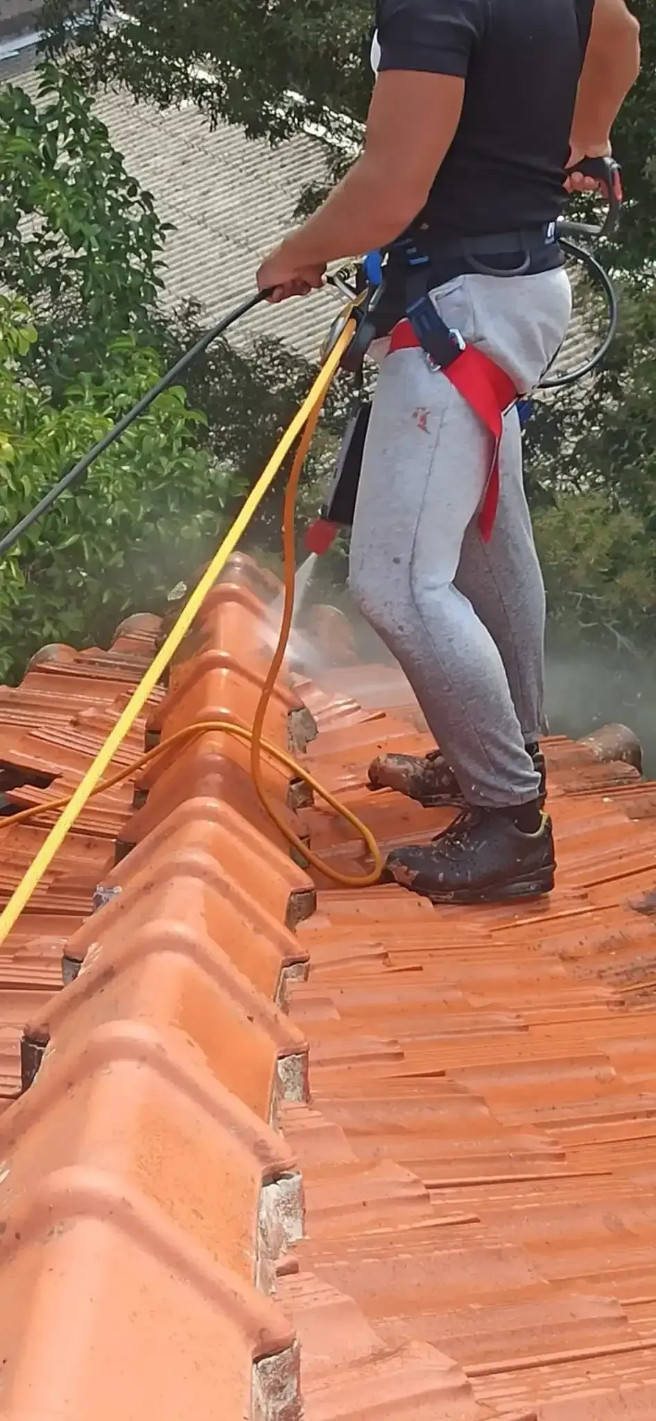 Um homem está limpando um telhado com uma lavadora de alta pressão.