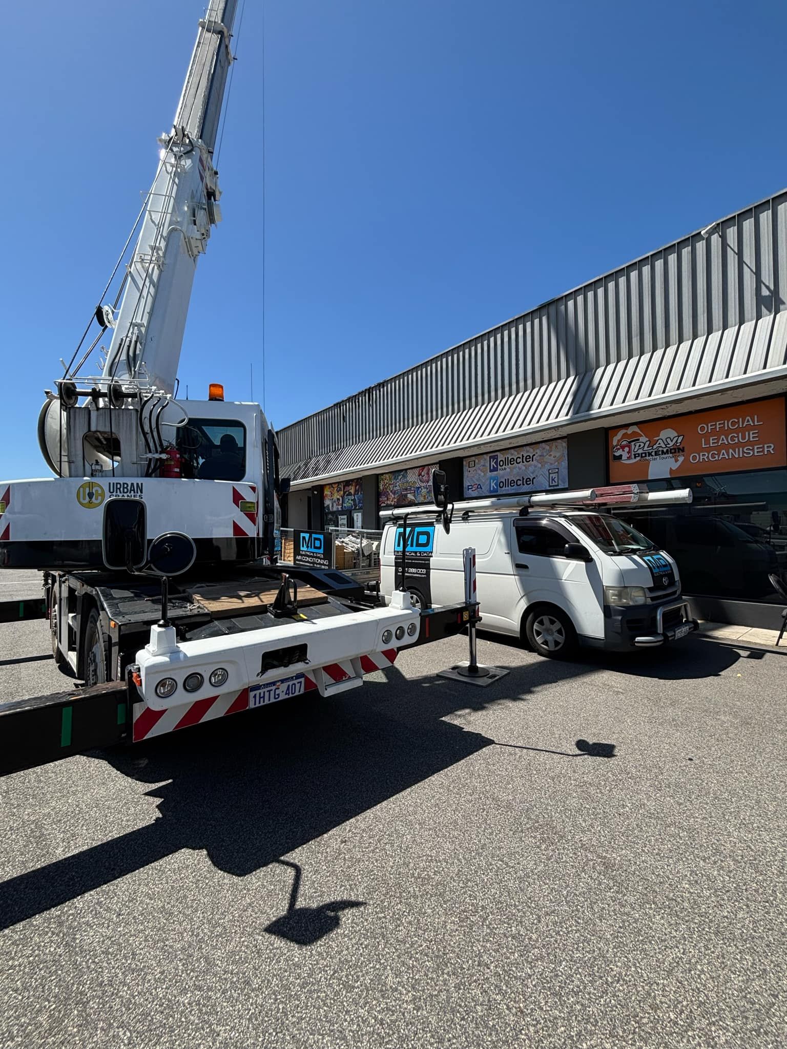 Commercial split system unit being hoisted on to warehouse roof by a crane