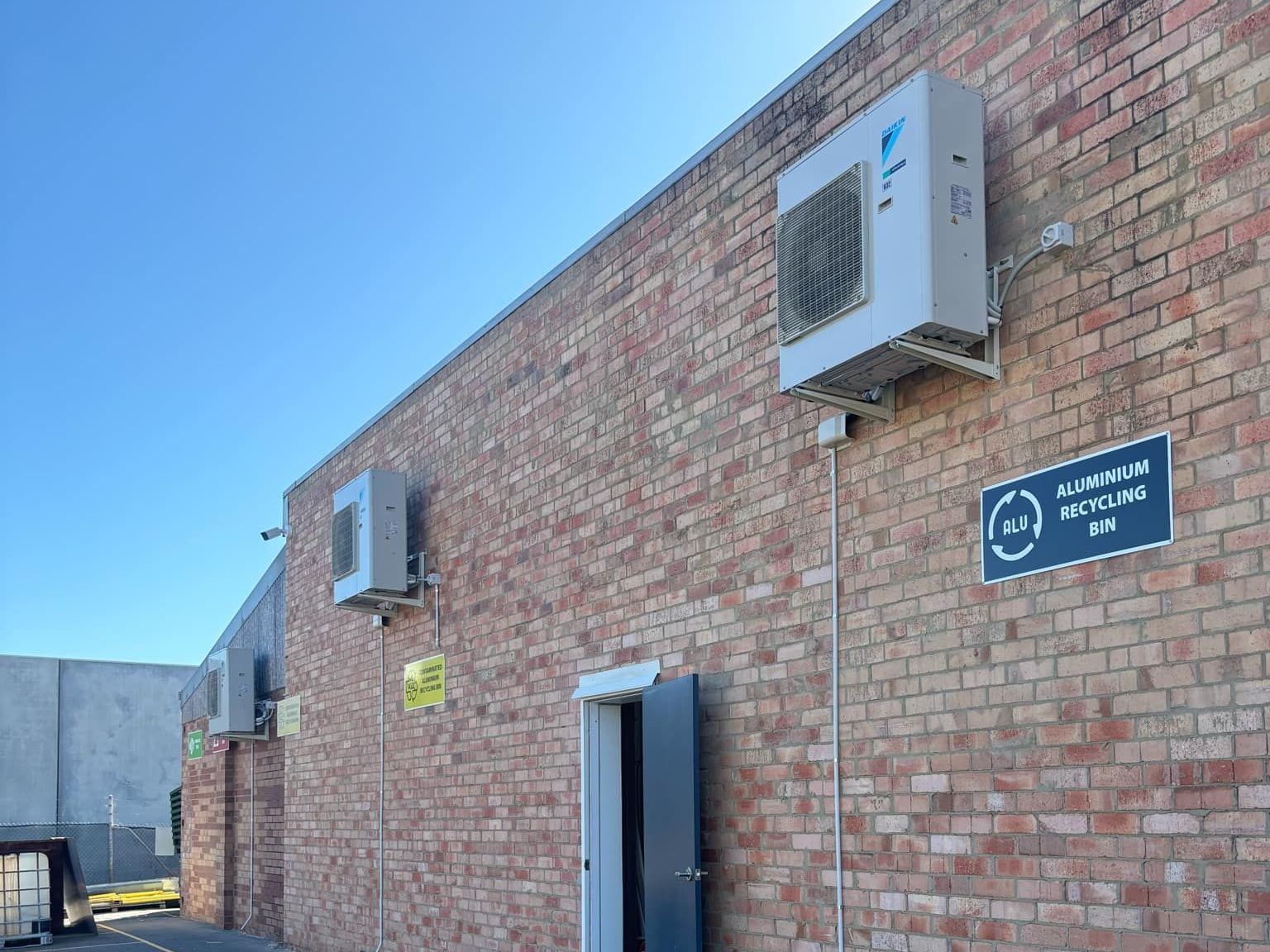 two commercial outdoor units mounted on wall of workshop.