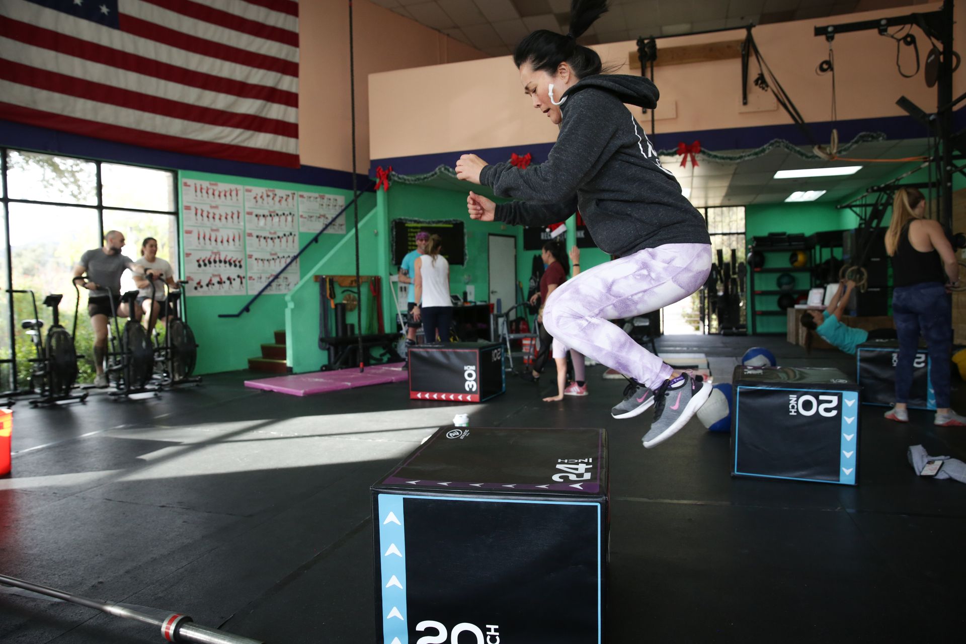 A woman is jumping over a box in a gym.