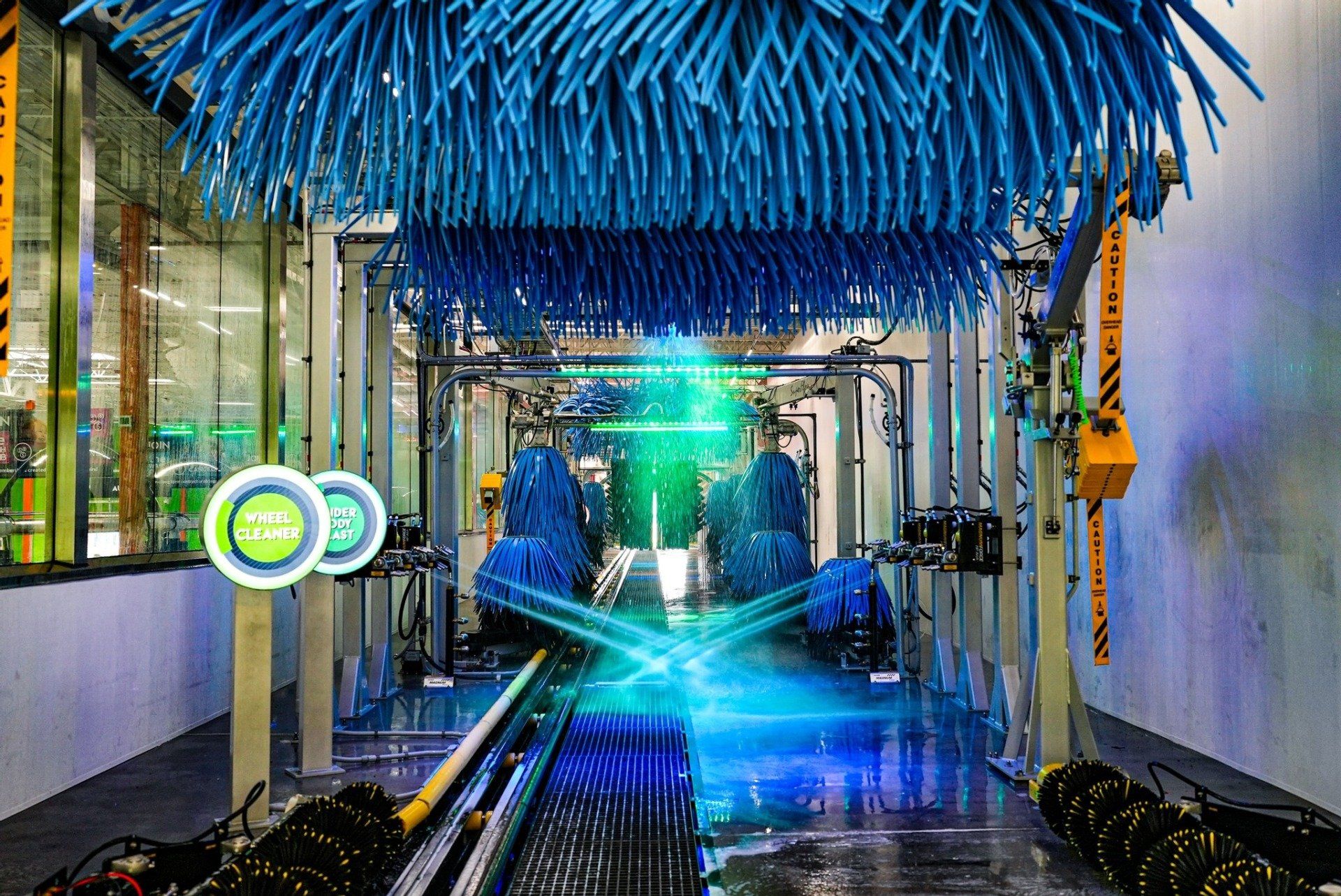 inside of a car wash with blue brushes and water spraying
