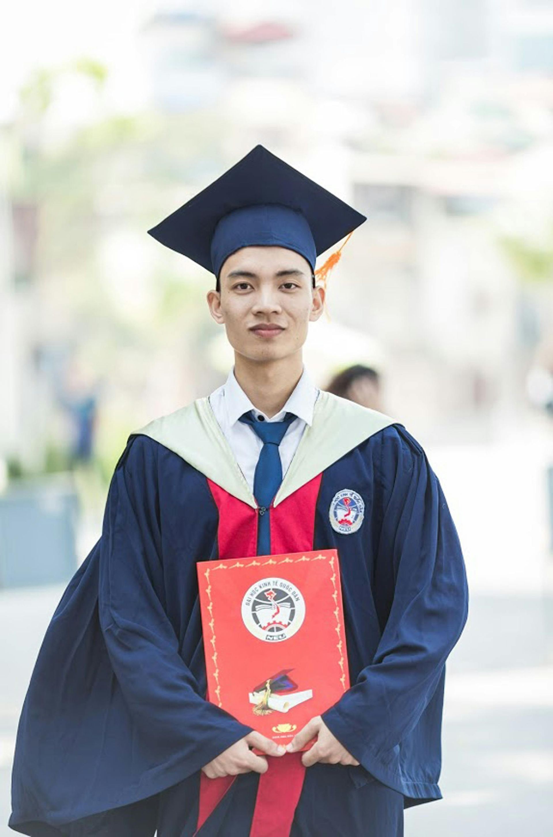 A man in a graduation cap and gown is holding a diploma.