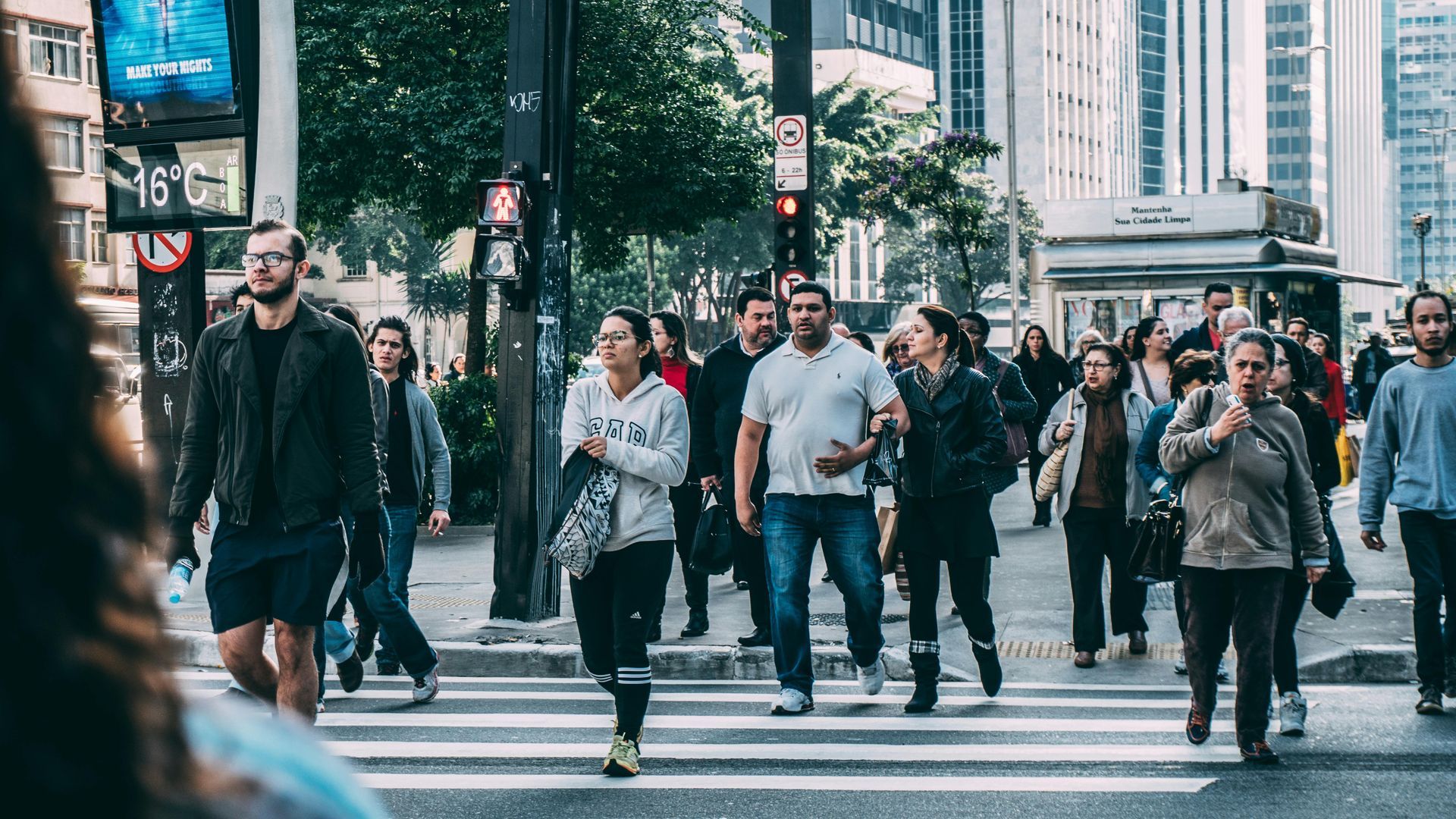 A large group of people are crossing a city street.