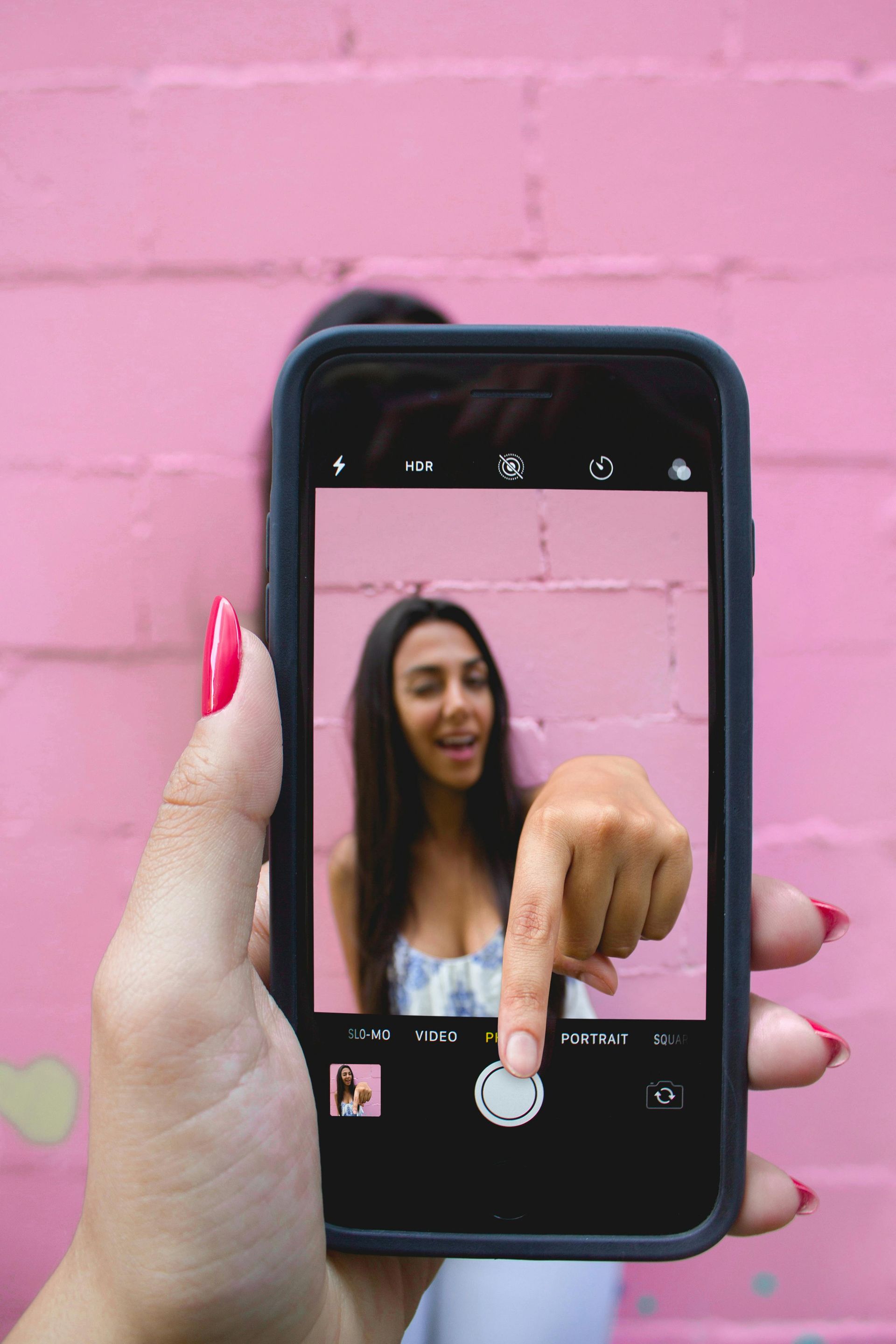 A woman is taking a picture of herself on her cell phone.