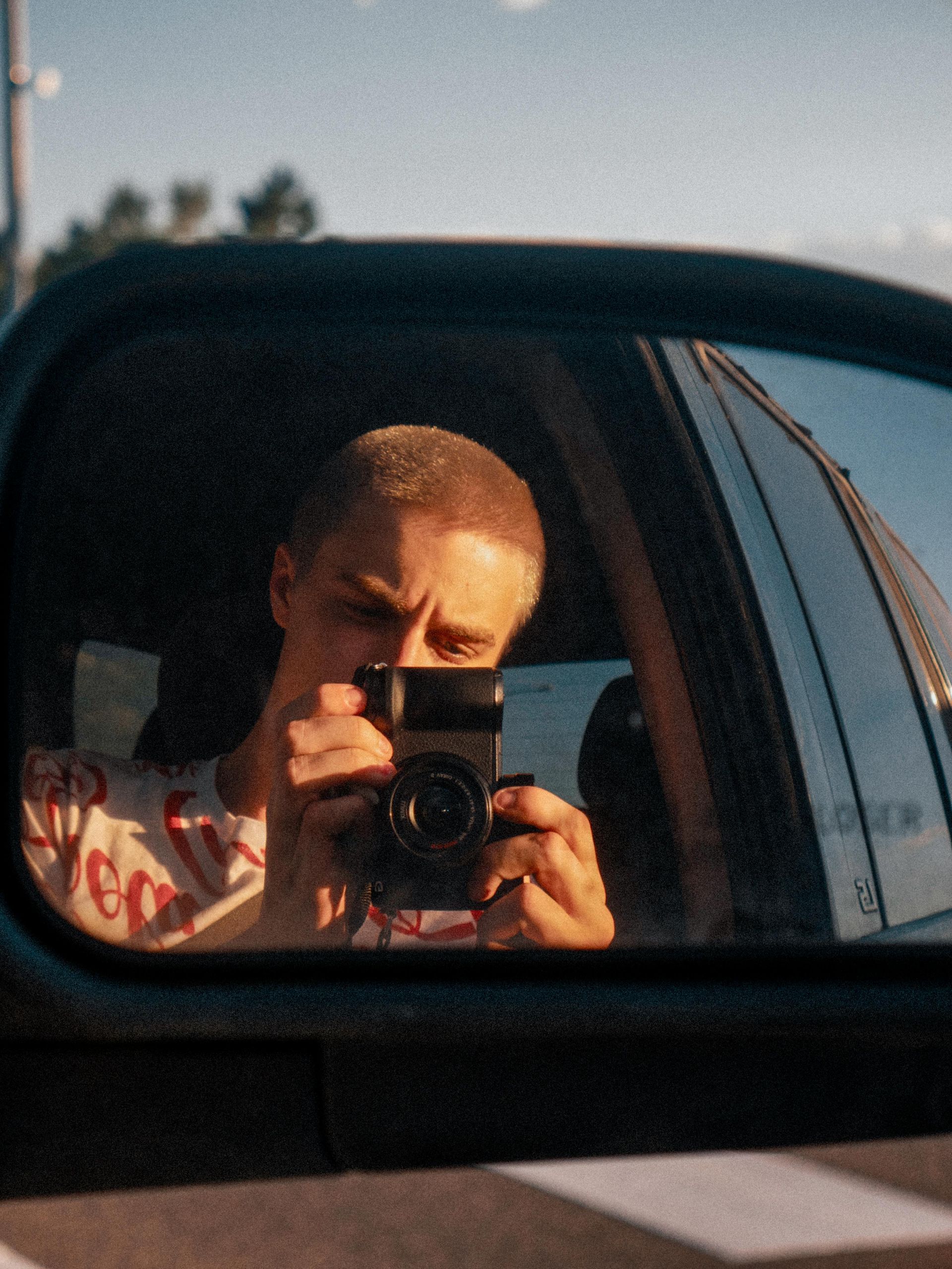 A man is taking a picture of himself in the rear view mirror of a car.