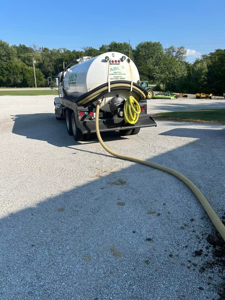 A septic tank truck with a hose attached to it is parked in a parking lot.