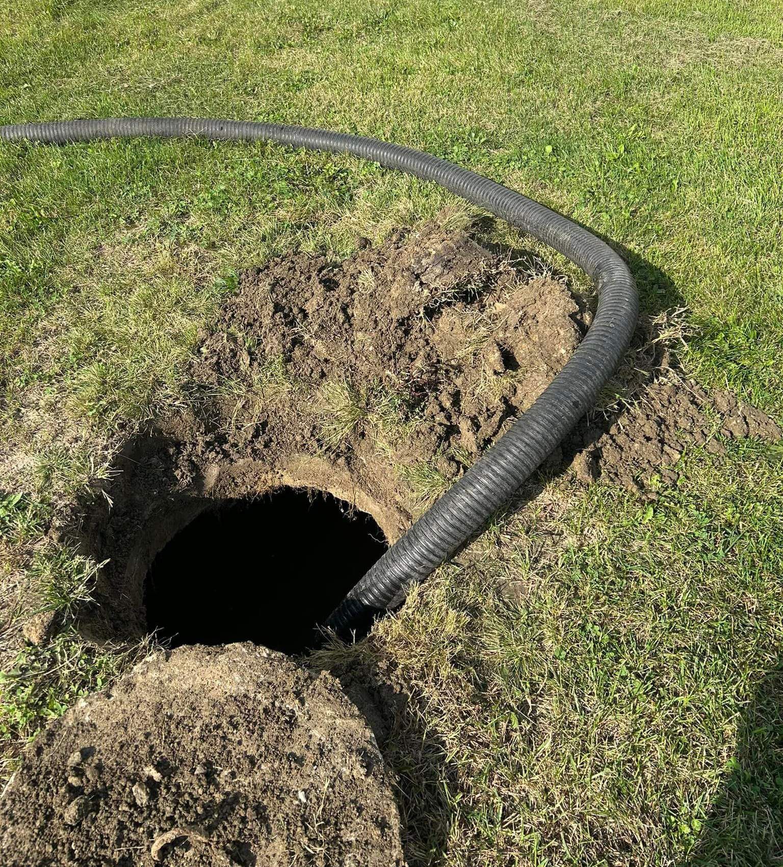 A hose is coming out of a hole in the ground.