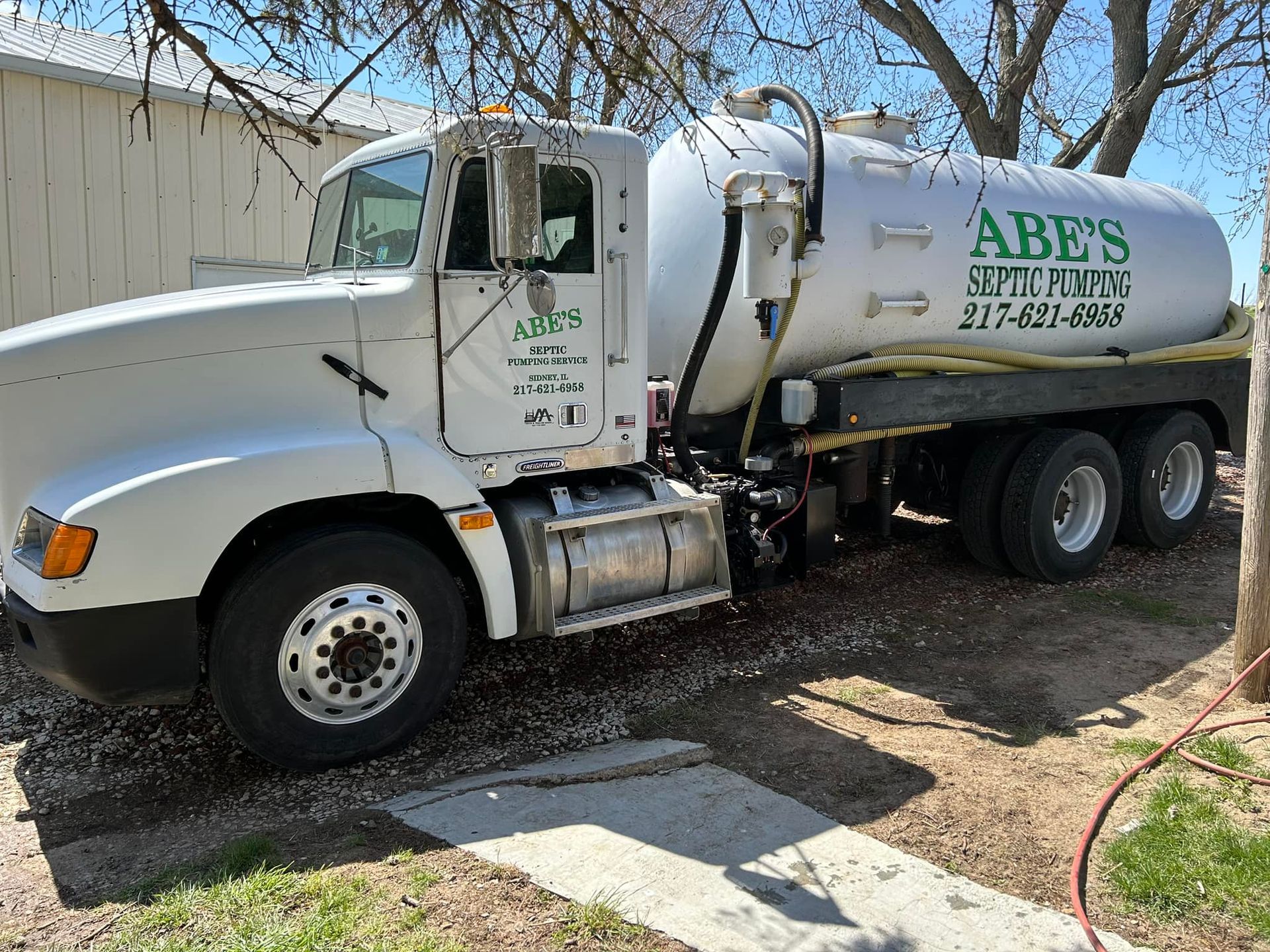 A white vacuum truck is parked in front of a building.