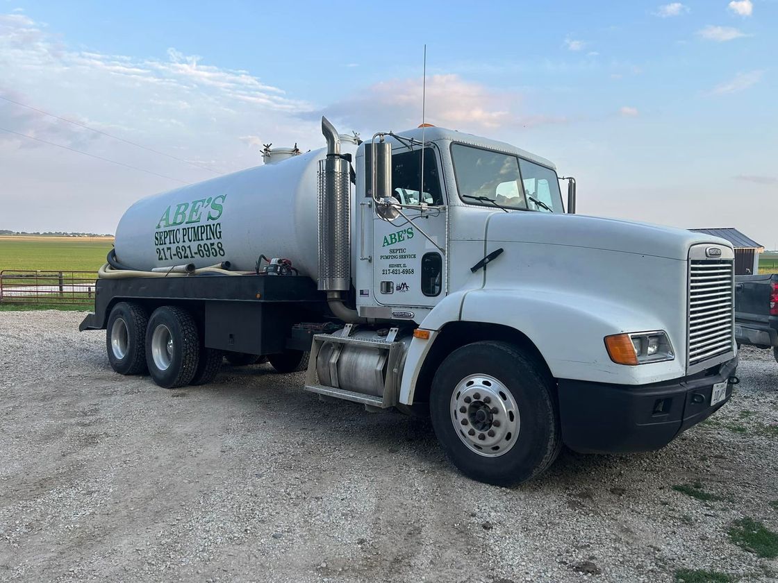 A large white truck is parked in a gravel lot.