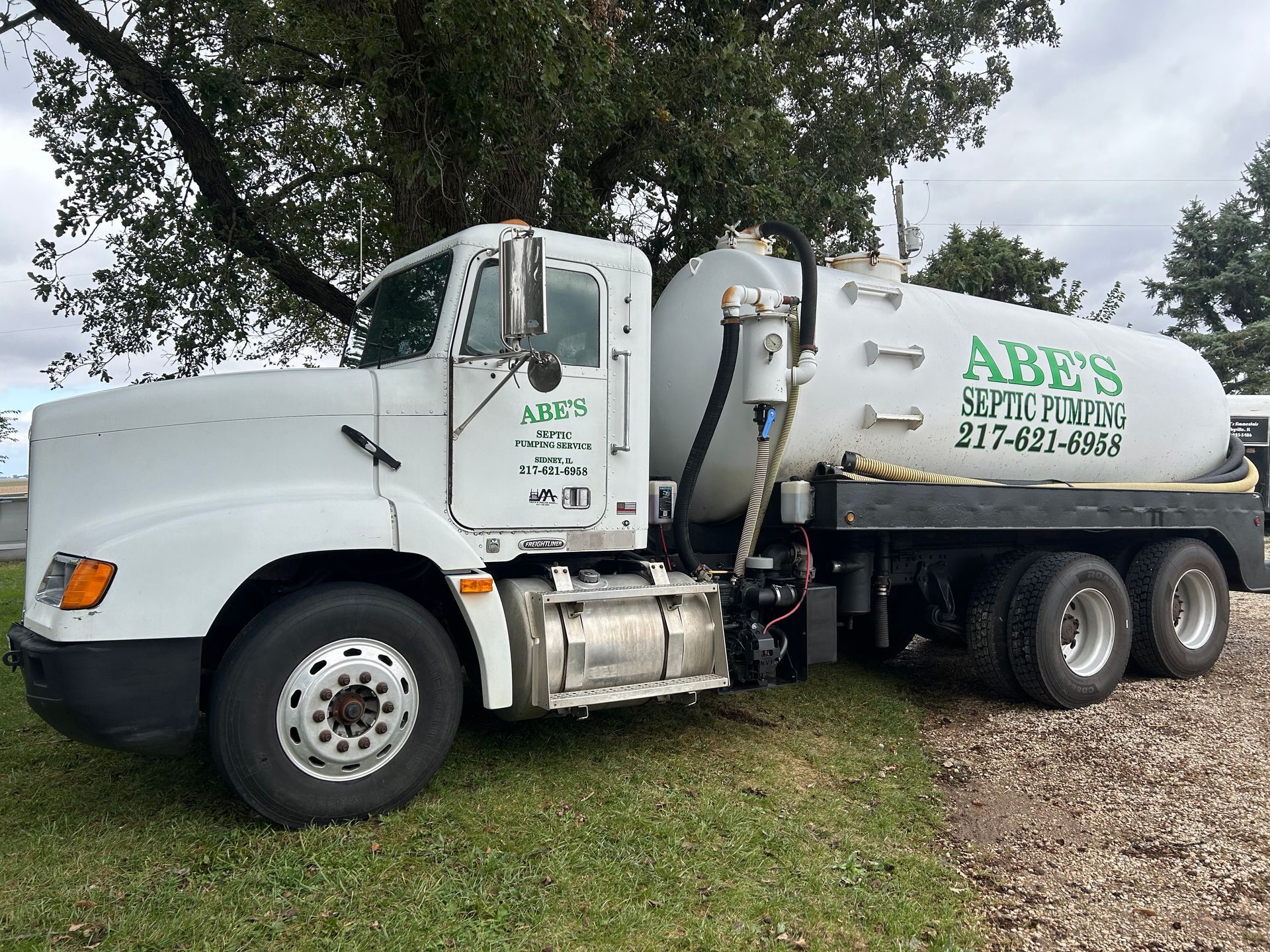 A man is standing in front of a septic pump truck holding a sign that says rapper full.