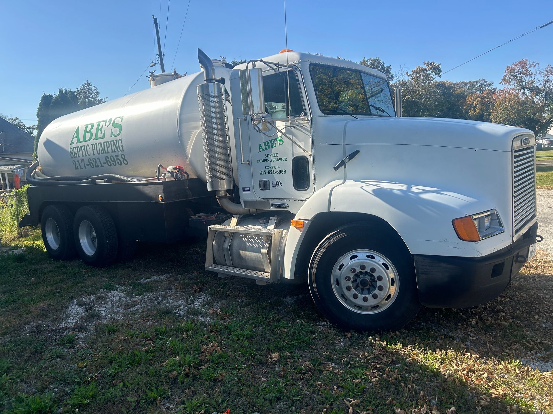 A man is standing in front of a septic pump truck holding a sign that says rapper full.