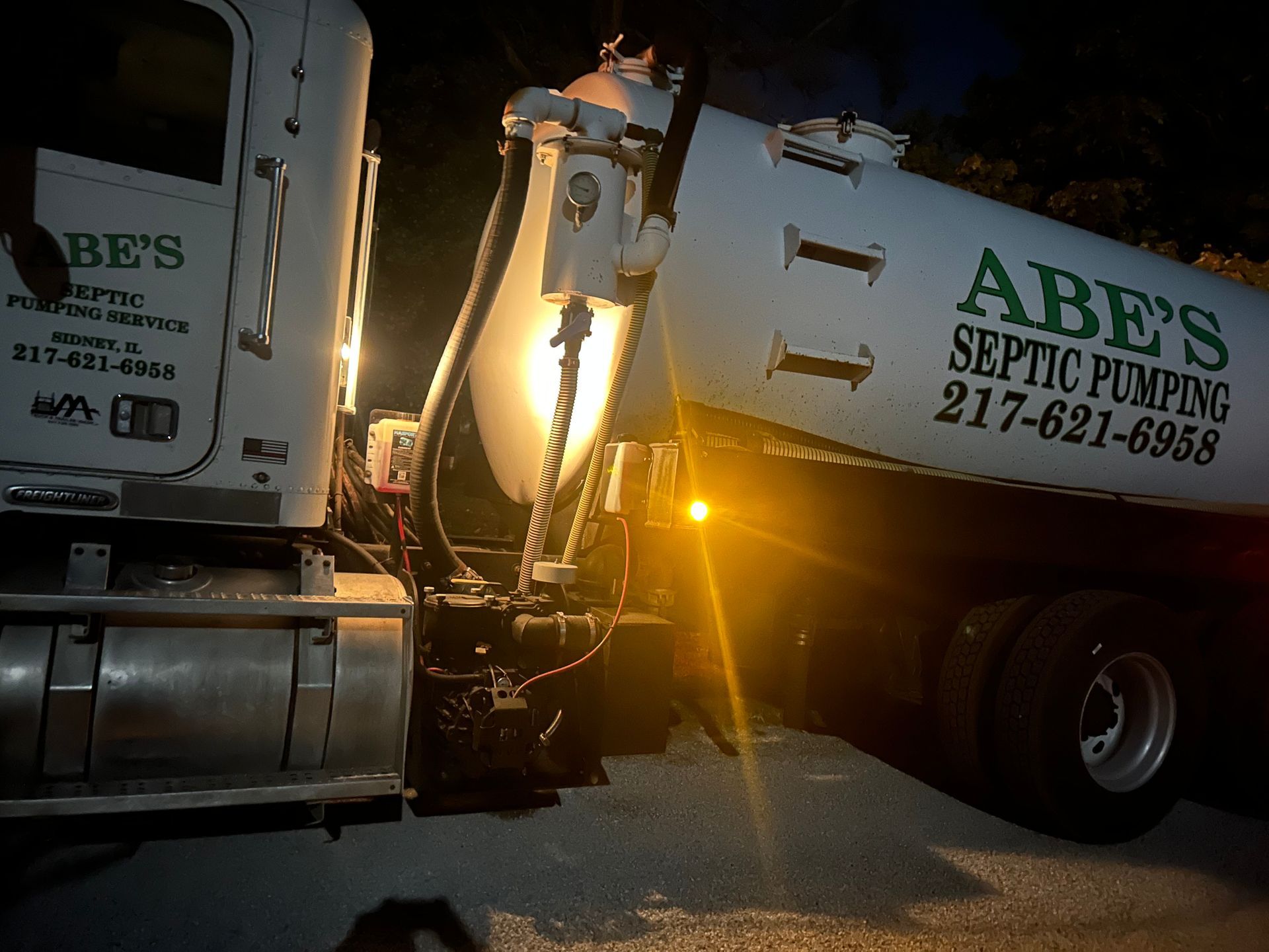 A man is standing in front of a septic pump truck holding a sign that says rapper full.