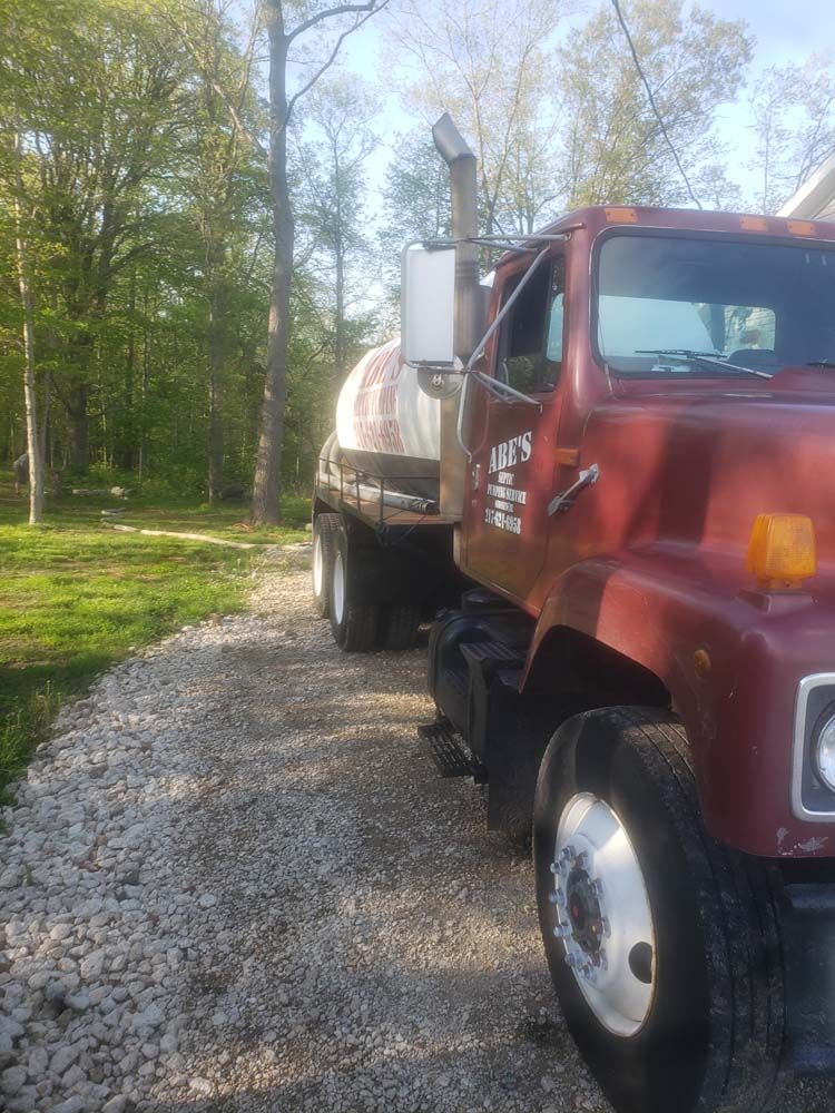 A red truck is parked on a gravel road.
