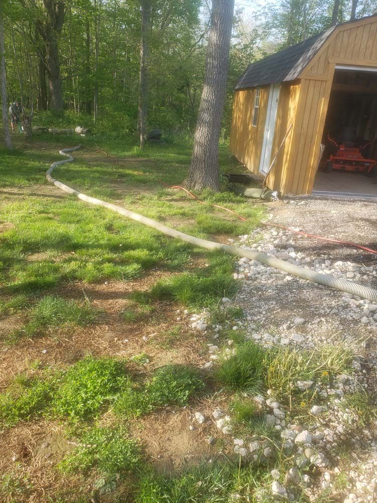 A hose is connected to a shed in the woods.