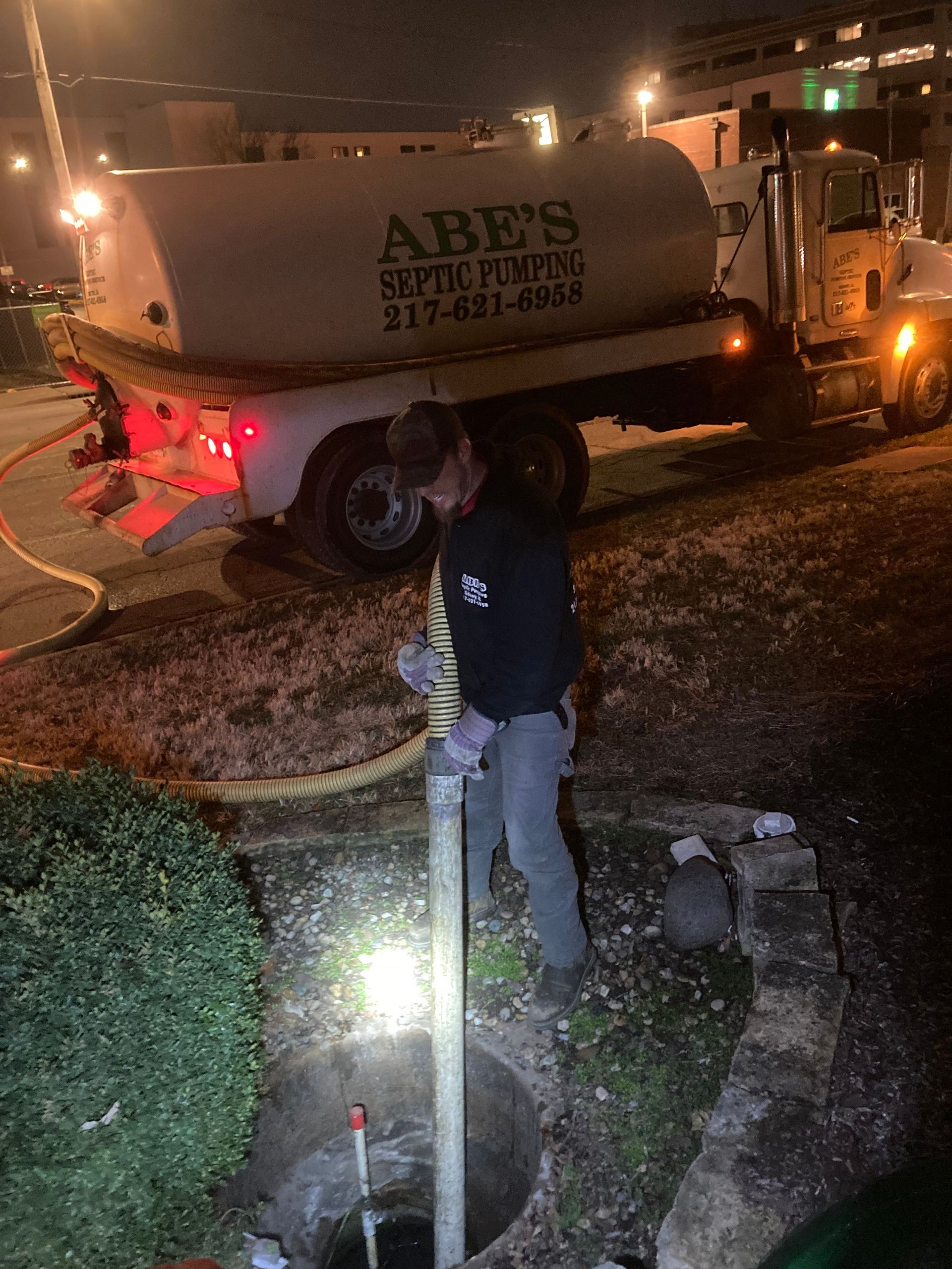 A man is standing in front of a septic pump truck.