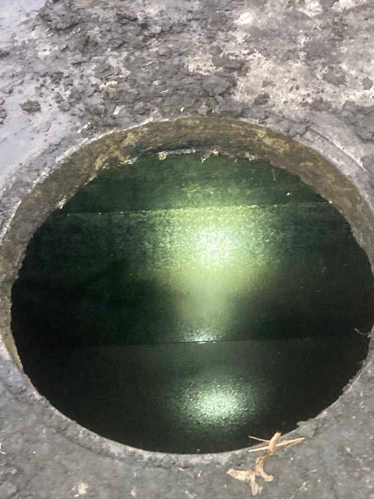 A hole in the ground with a light shining through it.