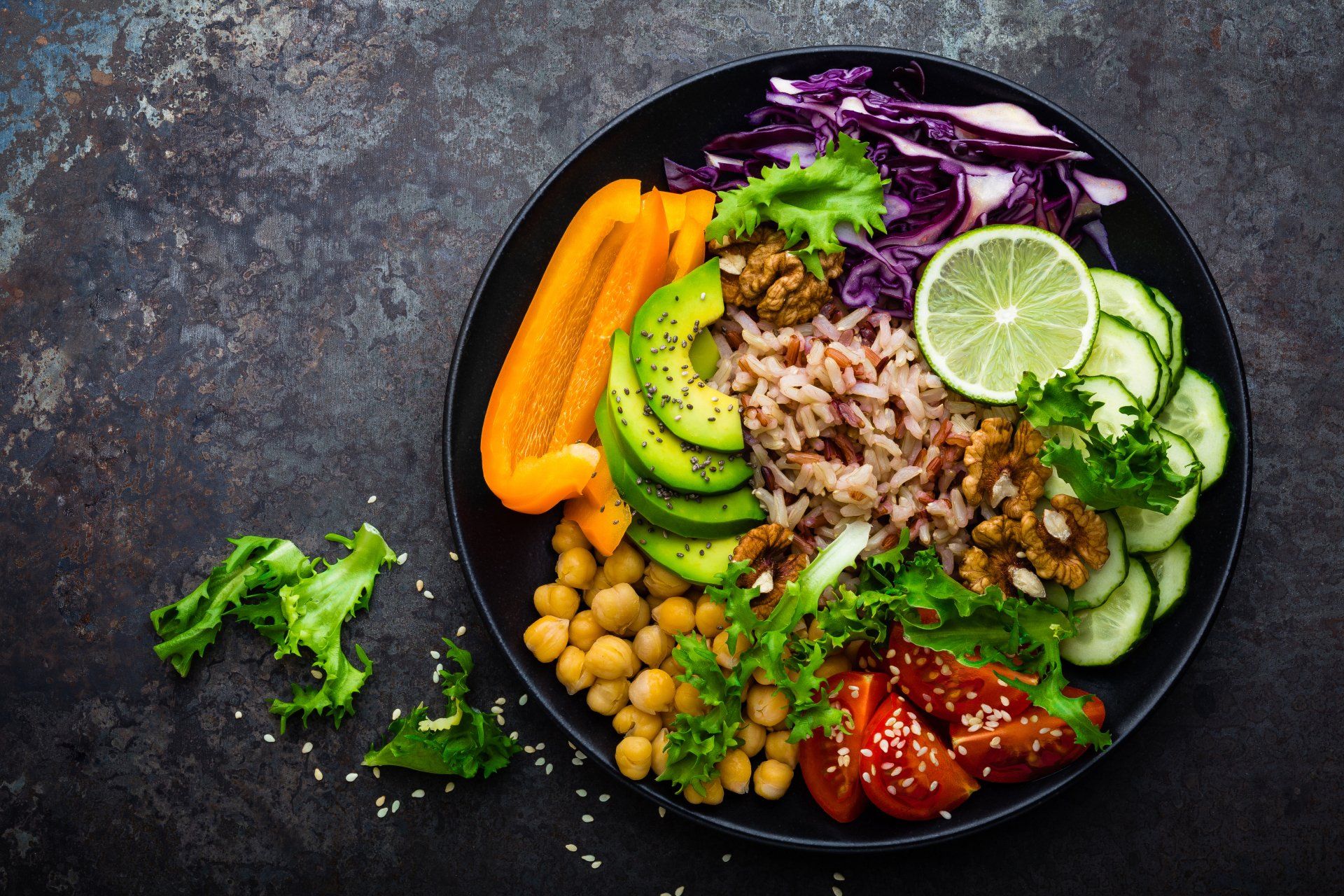 Healthy colorful bowl with vegetables, chickpeas, avocado, rice, and lime.