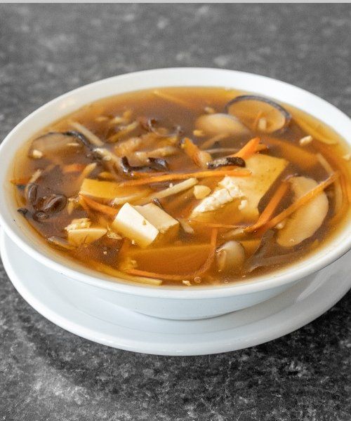 Bowl of hot and sour soup with tofu, mushrooms, carrots, and broth.